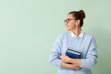 Canvas Print - Portrait of female teacher with books and pointer on color background