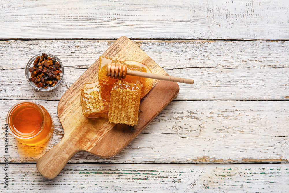 Jar of honey, combs and beebread on white wooden background