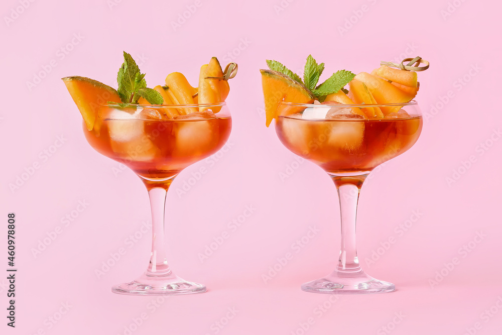 Glasses of delicious melon cocktail on pink background