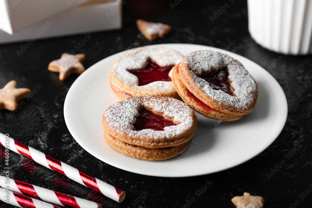 Plate with tasty Linzer cookies on dark background