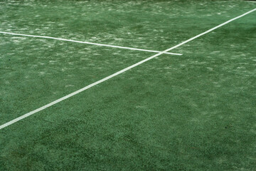 Texture of an outdoor sport court seen from above. Paddle tennis green cut with white lines.