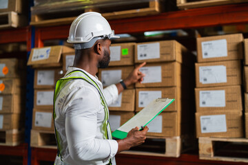 Wall Mural - Portrait of an African warehouse manager holding a clipboard checking inventory in a large distribution center.