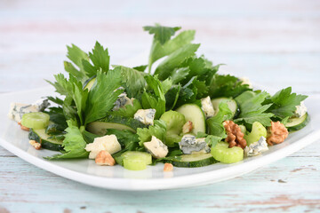 Wall Mural -  Celery leaves and stalks salad with fresh cucumber slices, blue cheese, crushed nuts.