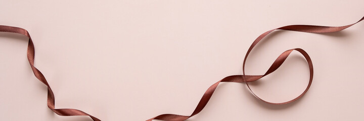 Satin brown ribbon on a beige background.