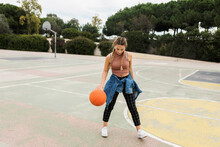 Woman Playing With Basketball At Sports Court
