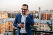 © Westend61 - Male business person with disposable cup talking on smart phone in balcony