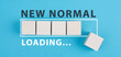 The words new normal are standing on wooden cubes, loading bar, blue colored background