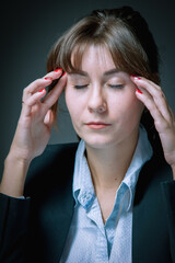 Portrait of unhappy and depressed business woman working overtime in office and having a headache from emotional stress. Vertical image.