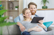 © auremar - young happy couple with digital tablet hugging on sofa