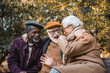 Cheerful interracial senior friends talking in autumn park