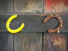 Two Rusty Horseshoes Hanging On A Wooden Door