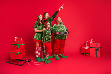 Sticker - Full size photo of santa helpers people point look empty space with sled giftboxes wear new year costumes isolated on red background