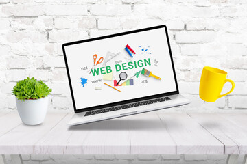 Wall Mural - Creative web design concept composition with laptop, coffee mug and plant levitating above the desk