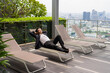 Asian businessman wearing suit and relaxing outdoors while laying down on sunbed in city