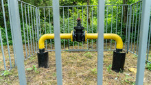 Gas Industry. The Locking Device Of The Gas Pipeline Passing In The Wood And Brought Outside, Protected By A Fence For Safety. Gas Distribution Station In The Forest. Yellow Gas Pipe