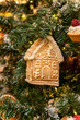 © IKvyatkovskaya - close up of gingerbread toy house s a christms tree decoration hanging on a fir branch. Symbol of new year and winter holidays