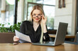 © splitov27 - Blond Caucasian business woman examines sheets of documents and sits at a table with a laptop in an outdoor cafe. Modern business woman. Lifestyle