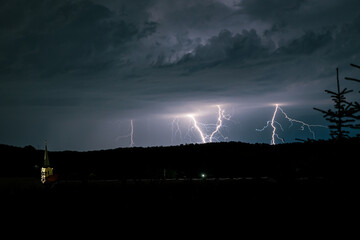 Wall Mural - multiple lightning bolts strike behind a hill in the landscape of transylvania, romania