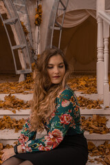 Wall Mural - Joyful youth stands leaning against a white railing young looking at the camera blonde in a colored shirt standing against the background of the steps laughing autumn standing dark mask blue eyes