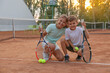 © New Africa - Cute children with tennis rackets and balls on court outdoors