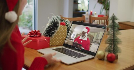 Sticker - Caucasian woman wearing santa hat having a videocall on laptop at home during christmas