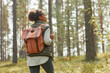 © Seventyfour - Back view portrait of young African-American woman with backpack enjoying hiking in forest lit by sunlight, copy space