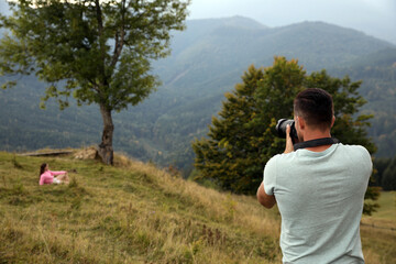 Sticker - Professional photographer taking picture of woman in mountains, back view