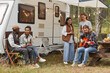 © Seventyfour - Full length view at group of young people relaxing outdoors by camper van in autumn, copy space