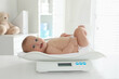 © New Africa - Cute little baby lying on scales in clinic
