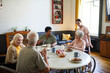 © Seventyfour - Warm-toned portrait of diverse group of senior people enjoying breakfast in cozy nursing home, copy space