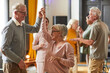 Leinwandbild Motiv Group of smiling senior people dancing while enjoying activities in retirement home, copy space