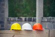© prachid - Safety helmet (hard hat) for engineer, safety officer, or architect, place on cement floor. Yellow, white, and orange safety hat (helmet) in construction site.
