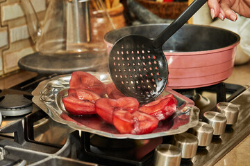 Sticker - Chef takes out ready-made pears cooked in red syrup with wine on the gas stove