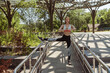 © Friends Stock - Woman in tracksuit stretches legs leaning onto metal railing in green park
