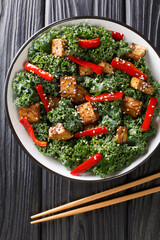 Wall Mural - Teriyaki tofu salad with peppers, kale and sesame seeds close-up in a bowl on the table. Vertical top view from above