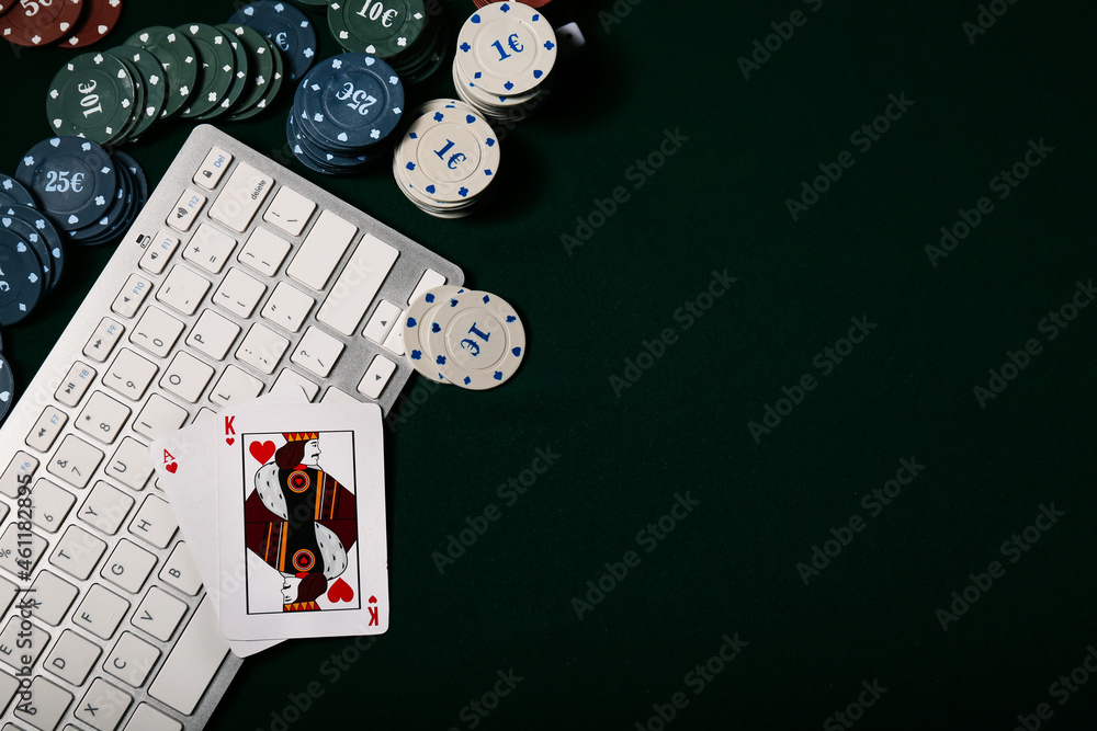 Computer keyboard, playing cards and poker chips on table in casino
