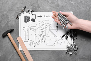 Wall Mural - Woman holding bolts, furniture assembling plan and different tools on grey background