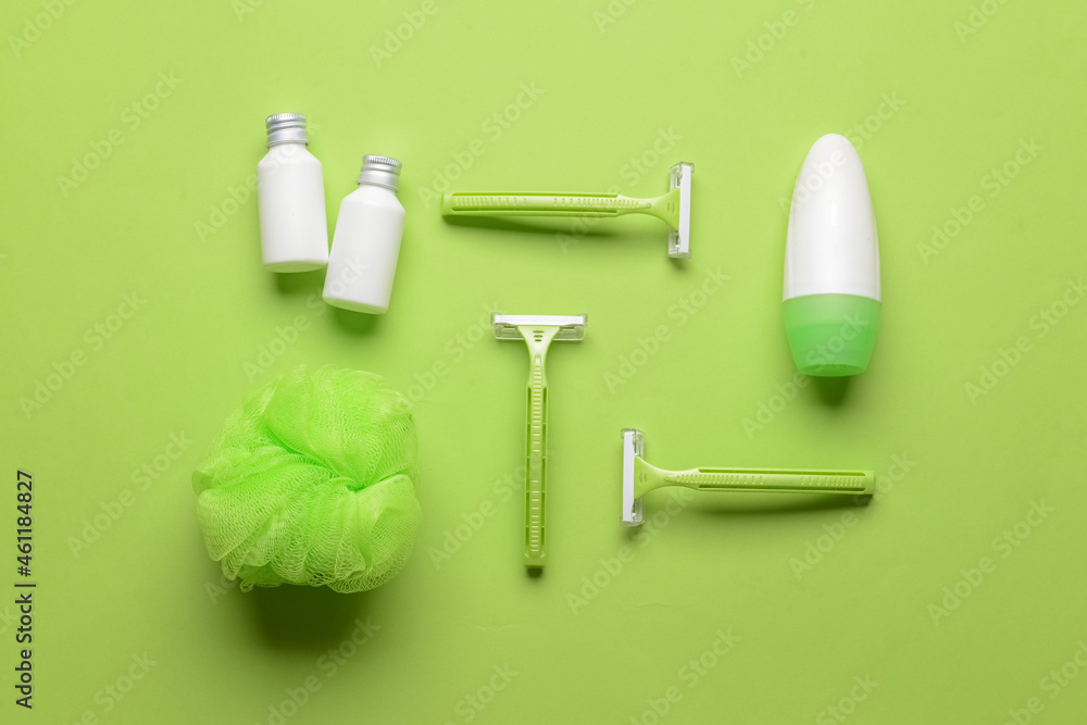 Safety razors, sponge and cosmetic products on green background