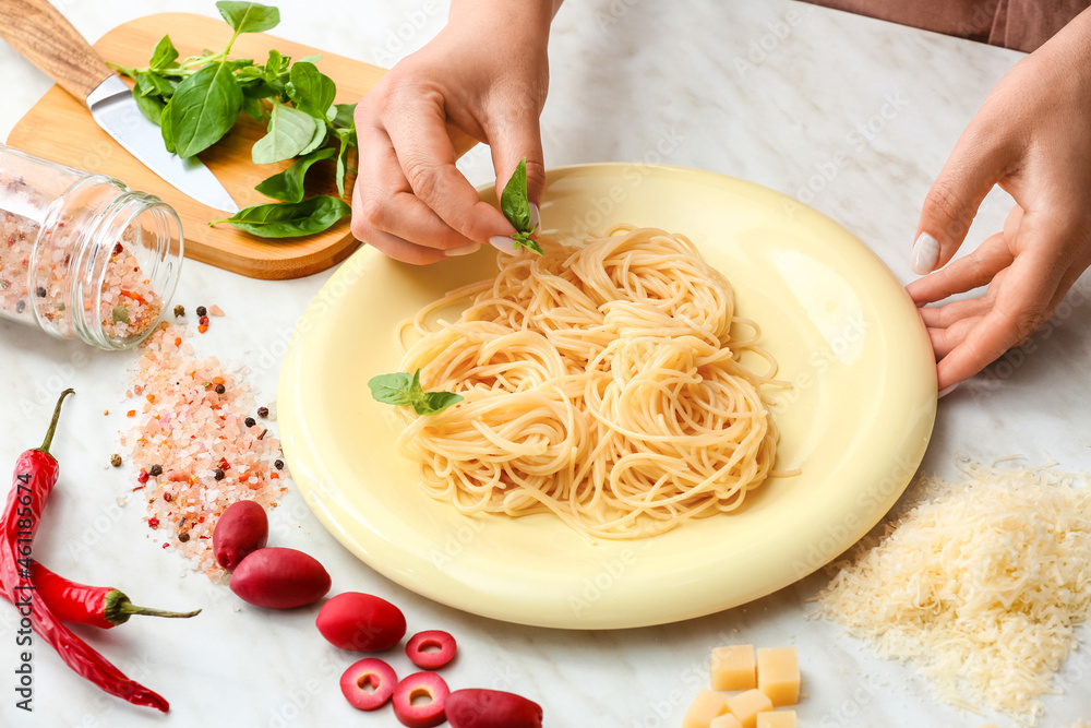 Woman preparing Pasta Puttanesca at kitchen table