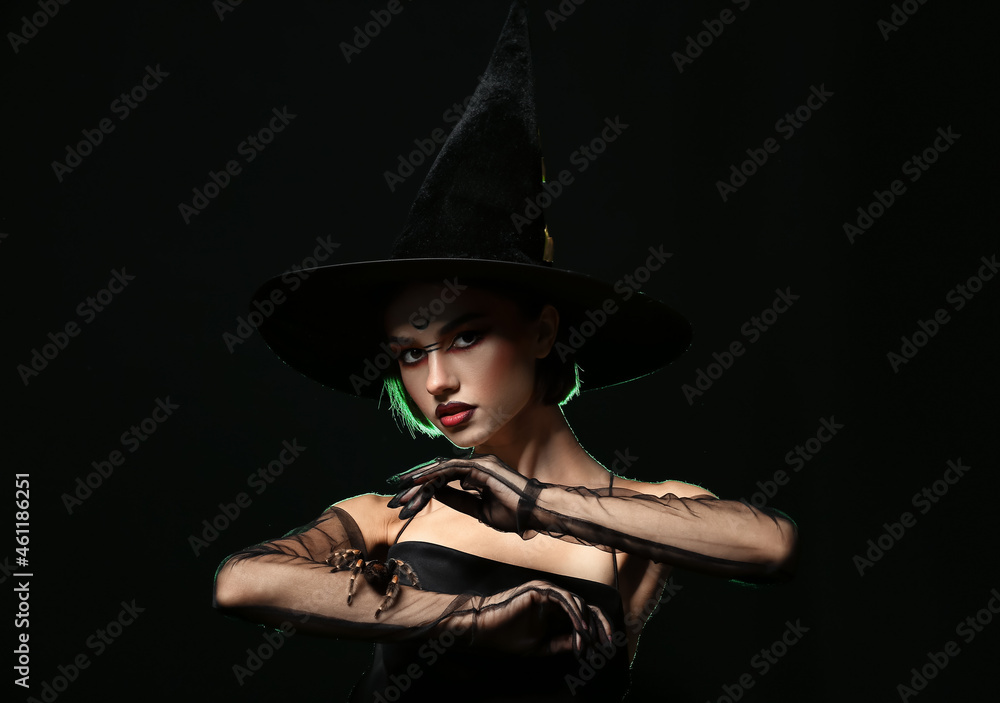 Young witch with spider on dark background