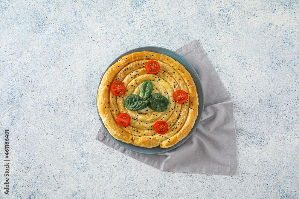 Plate with tasty spinach pie on light background