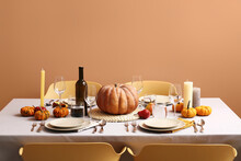 Autumn Table Setting With Fresh Pumpkins And Candles Near Beige Wall