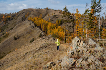 a little boy in a green jacket walking along a trail in the mountains, autumn climbing mountains, a walk in the park in the fresh air, a boy tourist, a young climber