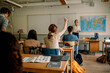© Maskot - Teenage girl raising hand in high school classroom