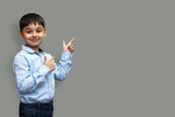 Fototapeta Sport - Smiling happy boy pointing finger away at copy space isolated over plain background