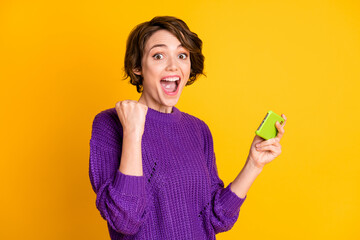 Poster - Photo portrait of cheerful screaming girl gamer holding phone vertically isolated on vivid yellow colored background