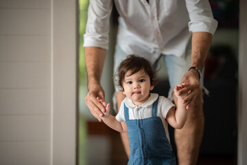 Wall Mural - father help children baby to walk, childhood family people with little cute toddler child son, happy learning in first step with support together from father at home