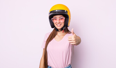 Poster - young pretty woman feeling proud,smiling positively with thumbs up. motorbike rider and helmet