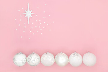 White Christmas bauble tree decorations with Bethlehem star symbol and snowflakes on pink background. Minimal abstract composition for the holiday season. Top view, flat lay. Copy space.