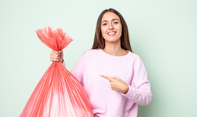 Poster - young pretty woman smiling cheerfully, feeling happy and pointing to the side. trash concept